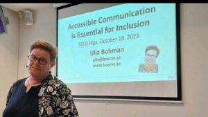 Ulla Bohman in front of screen that says Accessible Communication is Essential for Inclusion.
